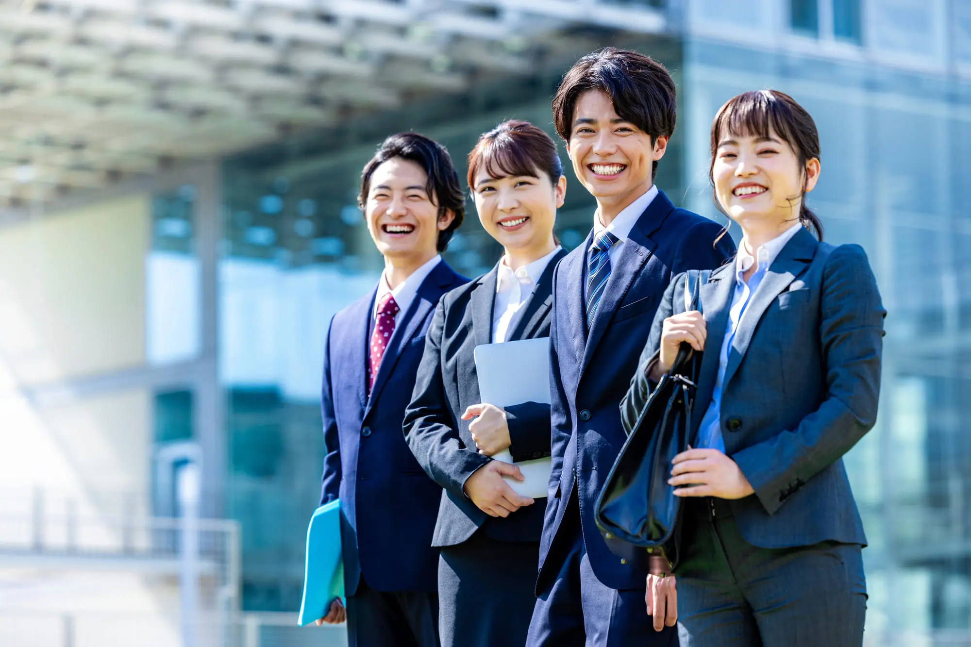 男女4人の若者が笑顔でこちらを見ている様子
