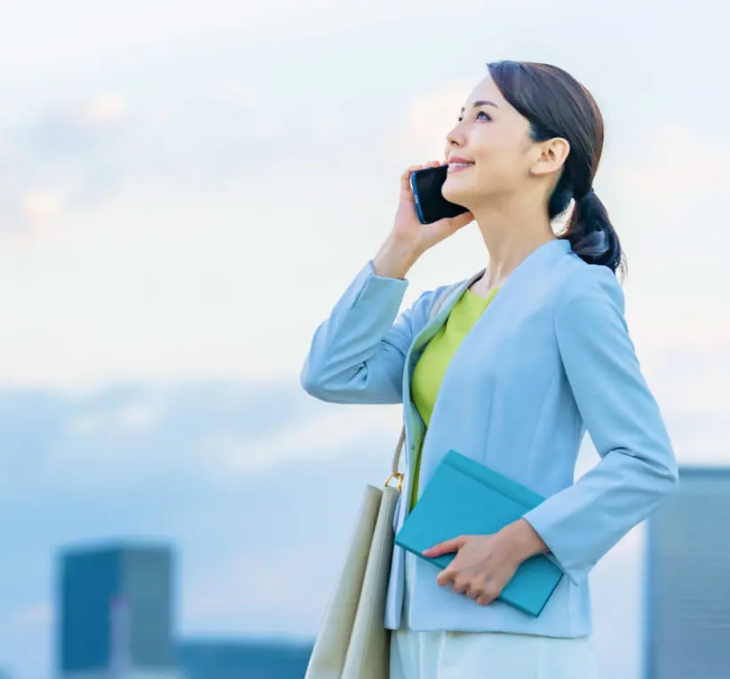 スマホで電話して青空を眺めている女性
